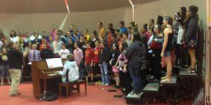 The choir prepares for their  concert tonight by practicing in the gym. 