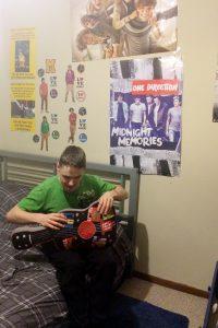 Brett Wheeler, sophomore, poses in his room with his One Direction merchandise 