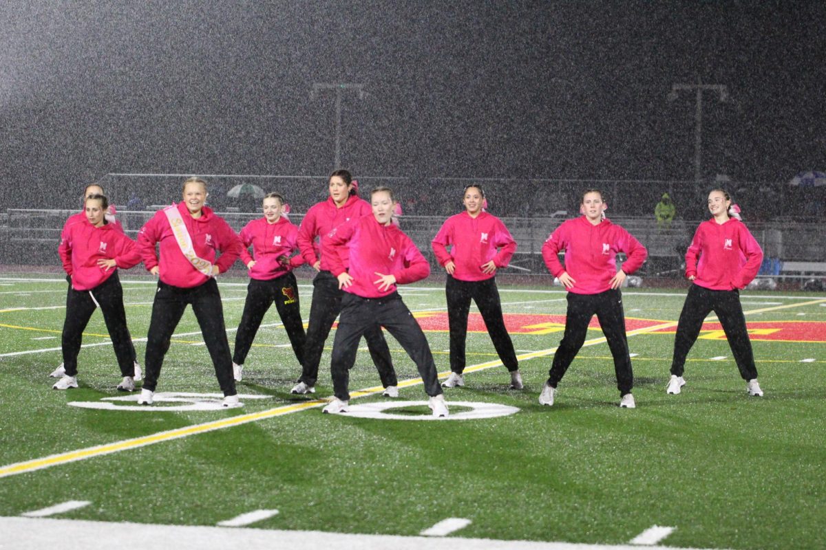 The poms team doesnt let the rain stop them during their senior night performance. 