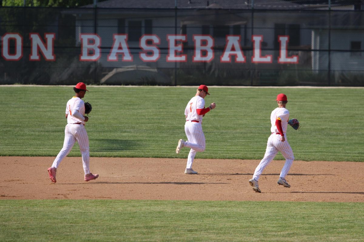 Three baseball players take the field during a summer game. 