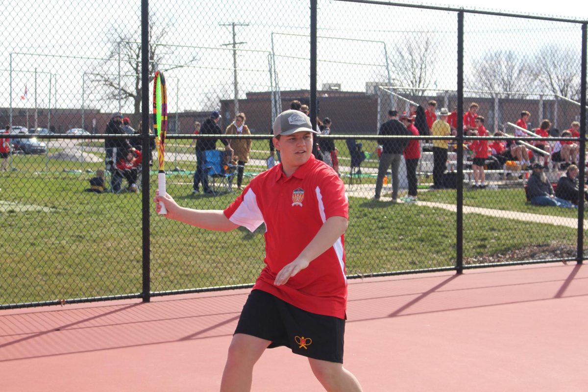 Jay Dunlavey prepares to hit the ball at the home tennis meet.