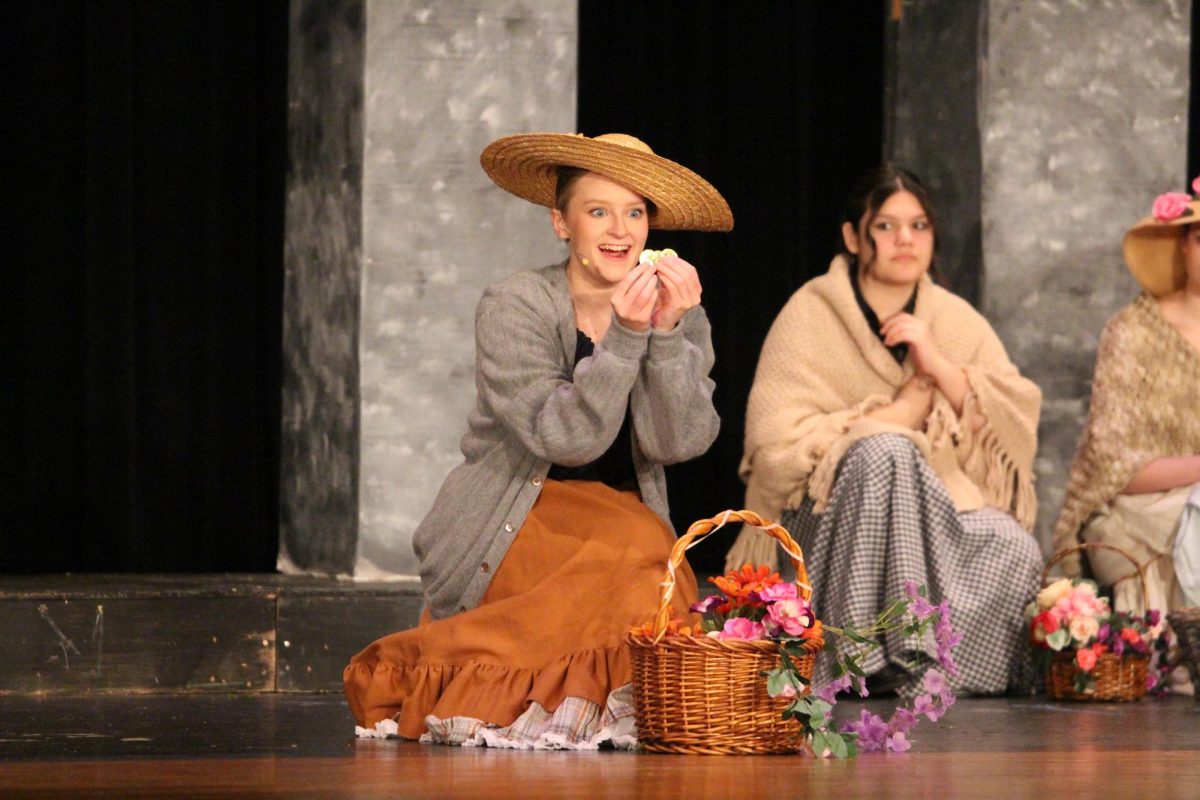 Hannah Andreasen, senior, marvels over her flower sale in the spring musical, My Fair Lady.