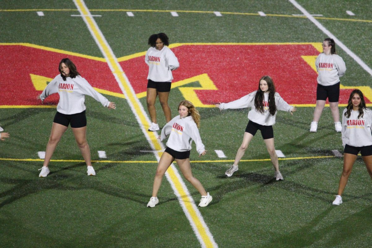 The poms football dance team performs under the friday night lights.