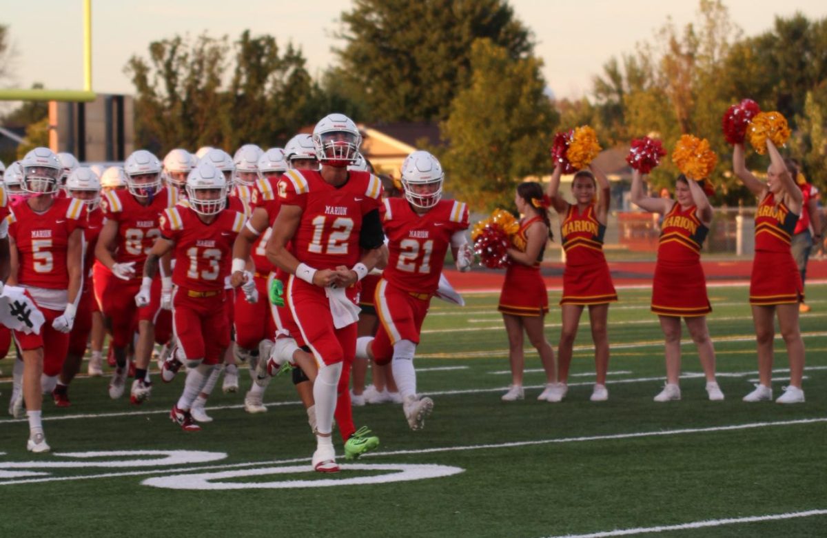 Kaleb Diers, senior, leads his team onto the field before the first home game as the cheerleaders hype them up. 