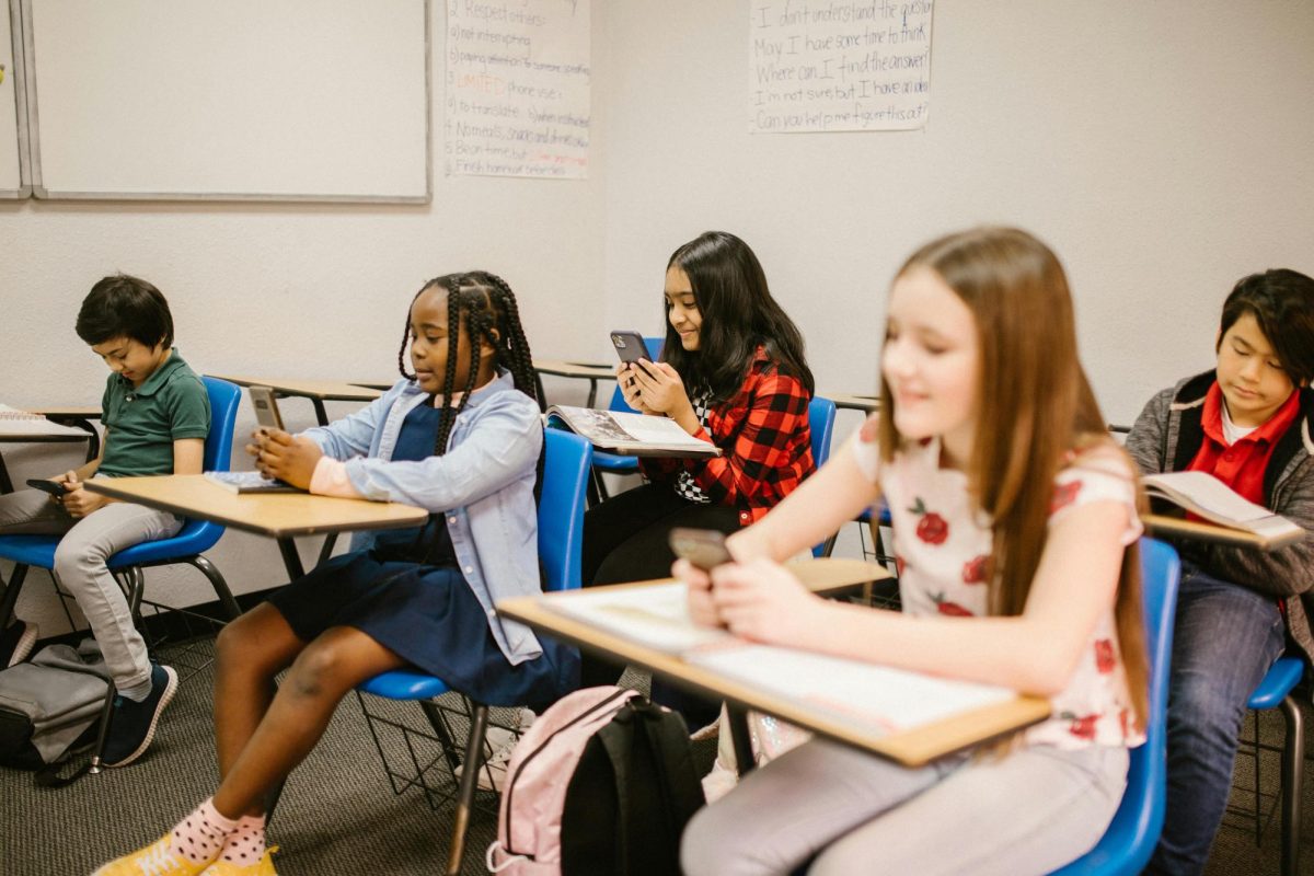 Multiple students interact with their phones instead of doing schoolwork.