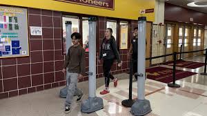 Students from a Wichita public school demonstrate walking through their new metal detector for the first time after experiencing a school shooting and drug use.
