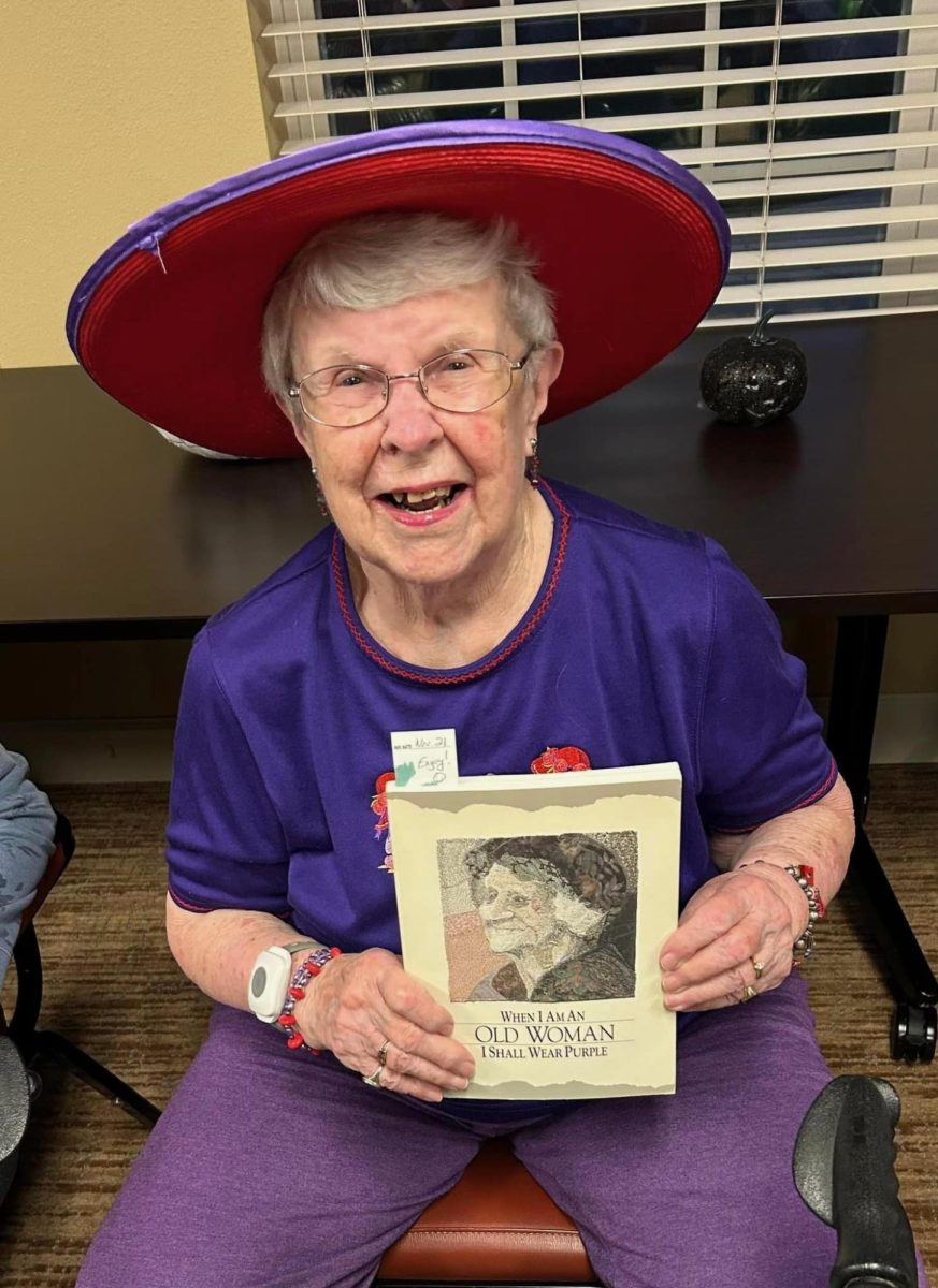 Mary Stuelke holds up one of her books, posing for a photo.