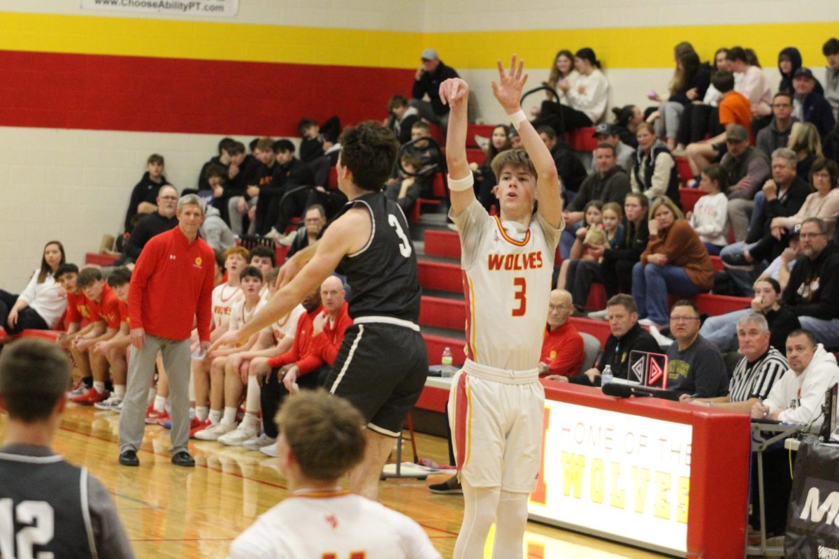 Mason Wagner, '25, makes a long-range jump shot as his team watches from the sidelines.